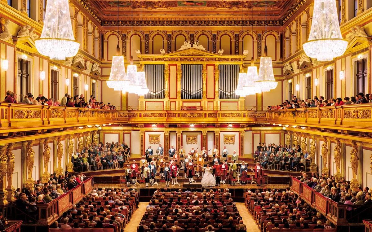 Period-costume performers and audience in a gilded concert hall at the Musikverein